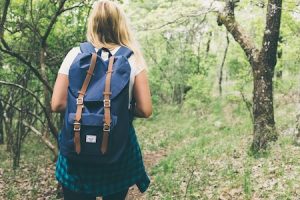 girl hiking in woods with blue backpack